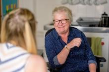 Older smiling woman looking at a younger woman that's only seen from behind