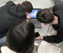 Photo of 3 younger people hovering over a laptop
